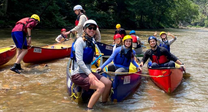 a group of students in canoes as they prepare to navigate whitewater on an outward bound trip 